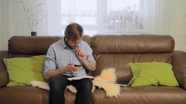 Jeune homme travaillant avec des documents et ses numéros de téléphone calcul — Video