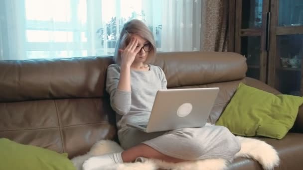 Jonge vrouw met behulp van een laptopcomputer moe en heeft een hoofdpijn — Stockvideo