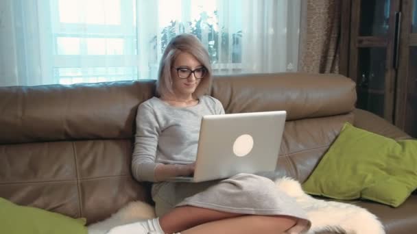 Feliz joven mujer está trabajando con su portátil, mirando a la cámara y sonriendo — Vídeo de stock