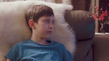 Genç çocuk evde televizyon izliyor.