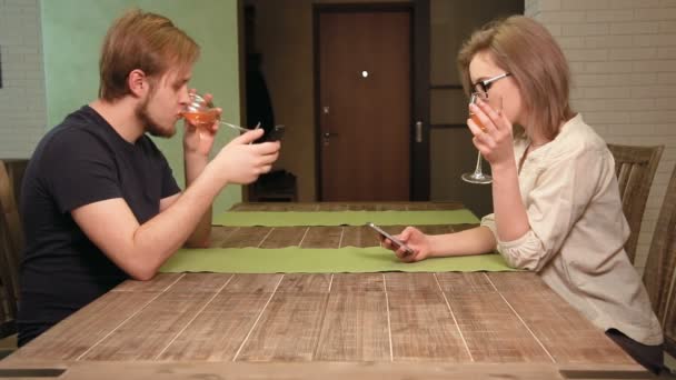 Giovane coppia su un appuntamento è annoiato navigare in Internet nei loro smartphone — Video Stock