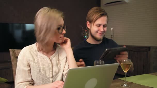 Casal jovem usando laptop e tablet digital, namorado mostra algo para sua namorada — Vídeo de Stock