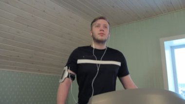 Bir koşu bandı üzerinde yürüme ve müzik genç adam