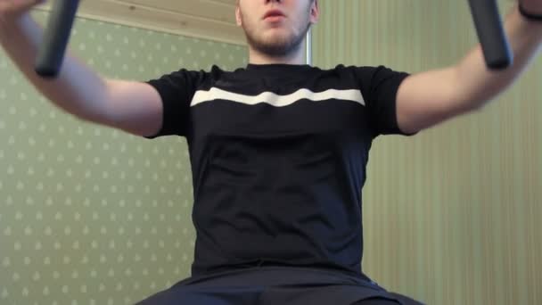 Mladý muž vyjde na jeho domovské tělocvičně zařízení vykonávat jeho svaly hrudníku — Stock video