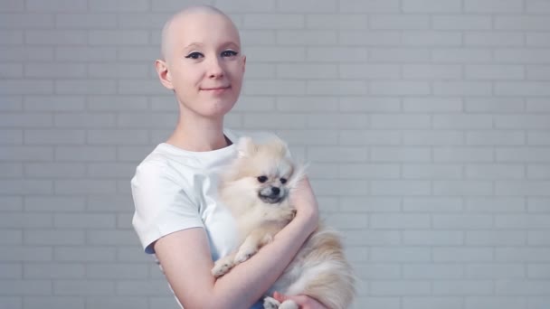 Glad cancer kvinna surviror leende tittar in i kameran och hålla söt liten hund spitz - breast cancer awareness koncept — Stockvideo