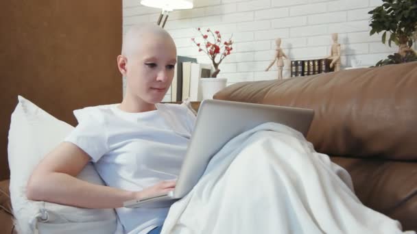 Mulher paciente de câncer deitada no sofá e usando seu laptop — Vídeo de Stock
