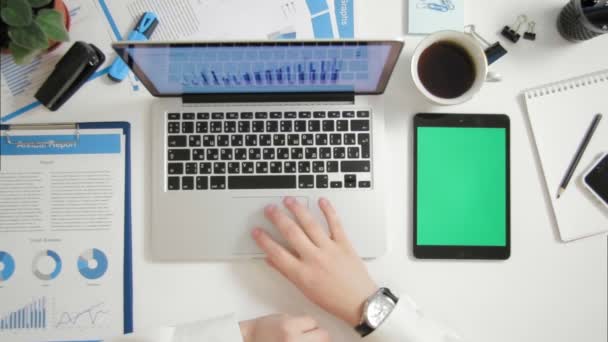 Ovanifrån affärsman arbetar på laptop på kontoret skrivbord med greenscreen digital tablett nära — Stockvideo