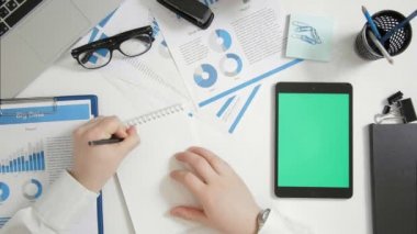 Üstten Görünüm işadamı oturan Ofis Masası ve not defterinde yazıyor, yeşil ekran dijital tablet yakınındaki