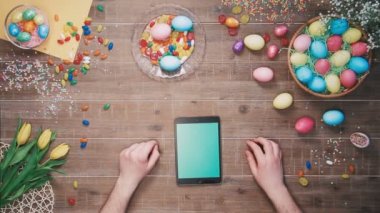 Dijital tablet masaya kullanan adam Paskalya yumurtaları ile dekore edilmiştir. Üstten Görünüm