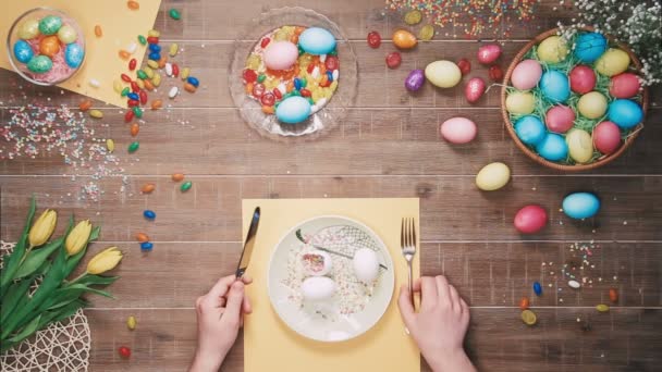 Ember tartja a kést és a villát előtt lemez húsvéti tojás húsvéti tojás díszített asztalon. Szemközti nézet