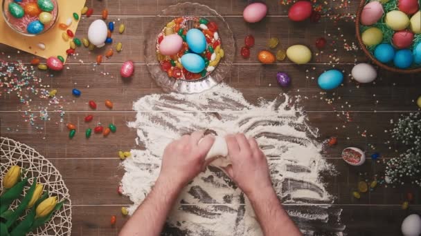 Hombre amasando masa en la mesa decorada con huevos de Pascua. Vista superior — Vídeos de Stock