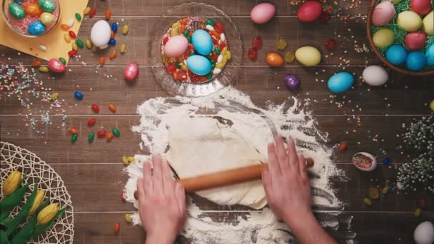 Hombre amasando masa en la mesa decorada con huevos de Pascua. Vista superior — Vídeos de Stock