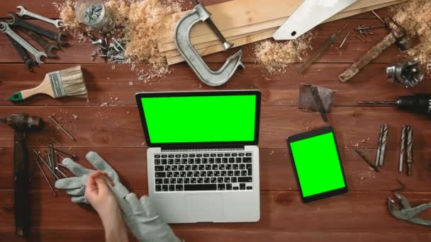 Top vista mãos artesão trabalhando no computador portátil e tablet digital deitado sobre a mesa com tela verde — Vídeo de Stock