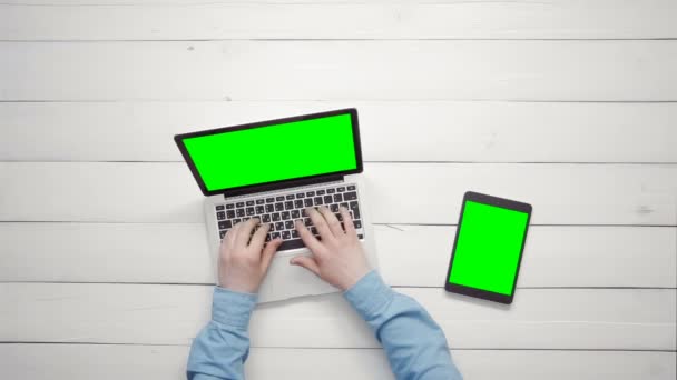 Vue du dessus mains masculines travaillant sur ordinateur portable et tablette numérique couché sur bureau blanc à partir de l'espace de copie ci-dessus — Video