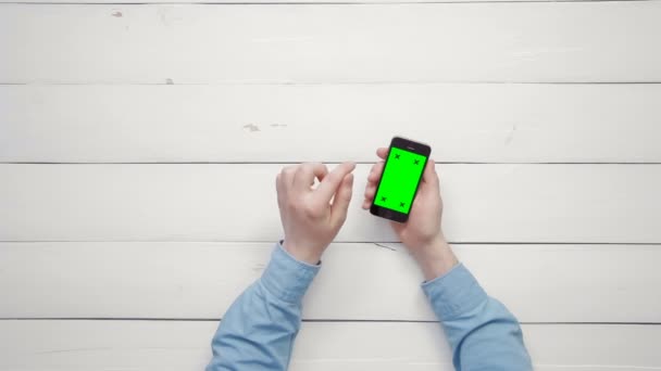 Ovanifrån manliga händer visar flera gester på smartphone med grön skärm på vita skrivbord ovanifrån kopia utrymme — Stockvideo