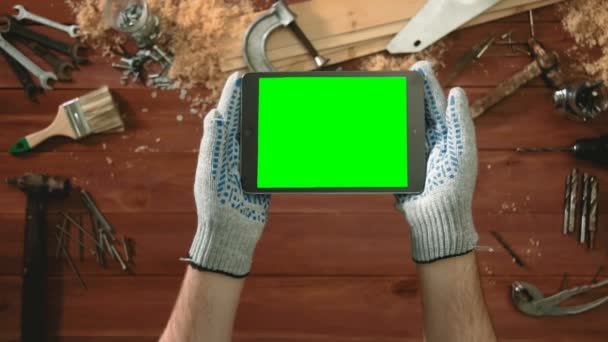 Pohled shora řemeslník ruce v rukavicích drží digitální tabletu ve vodorovném směru se zelená obrazovka