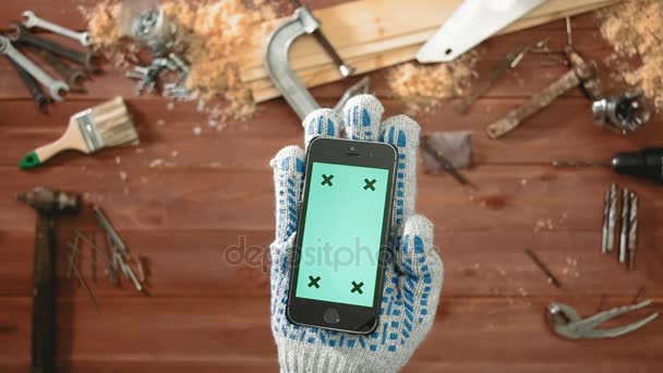 Top view craftsman hand in glove holding smartphone with green screen — Stock Video