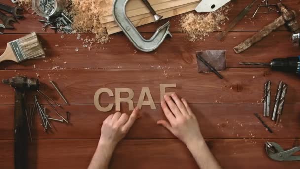Вид сверху на временной промежуток руки, лежащей на влажном столе со словом "CRAFT" " — стоковое видео