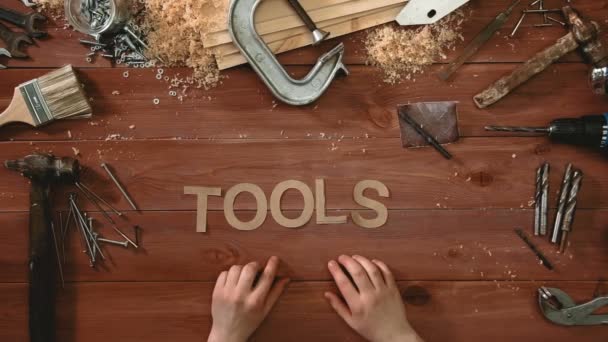 Top view time-lapse of a hand laying on wodden table word "TOOLS" — Stock Video