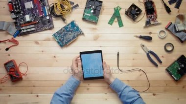 Üstten Görünüm bilgisayar teknisyeni devre kartı anahat araçları ve elektronik bileşenler ile ahşap masa ile dijital tablet kullanma