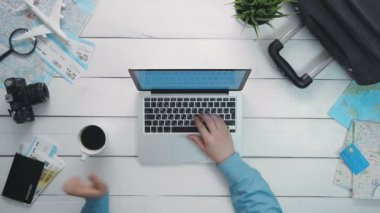 Beyaz ahşap masa başında dizüstü bilgisayar kullanan üstten görünüm yolcuları eller