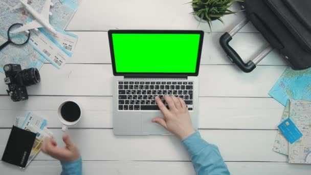 Bovenaanzicht reizigers handen laptopcomputer met groen scherm op witte houten bureau — Stockvideo