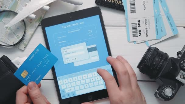 Reisende bezahlen Flugtickets online mit digitalem Tablet und Kreditkarte an weißem Holztisch — Stockvideo