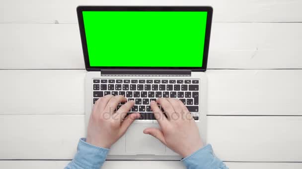 Bovenaanzicht mannelijke handen werken op laptopcomputer met groen scherm op witte Bureau above kopie ruimte — Stockvideo