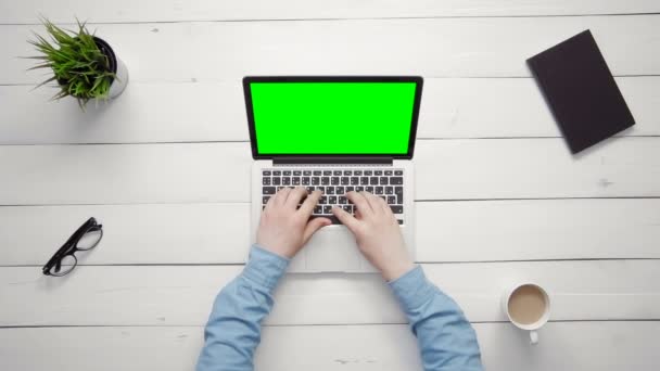 Vista dall'alto mani maschili che lavorano su computer portatile con schermo verde alla scrivania bianca dall'alto — Video Stock