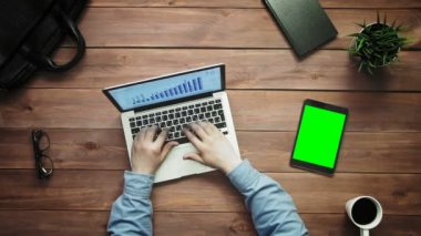 Üstten Görünüm erkek yeşil ekran yukarıdan beyaz masa üzerinde yalan ile dizüstü bilgisayar ve dijital tablet üzerinde çalışan eller