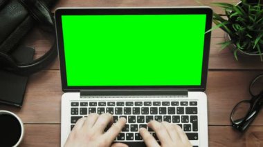 Üstten Görünüm erkek yukarıdan beyaz masada yeşil ekranlı dizüstü bilgisayar üzerinde çalışan eller
