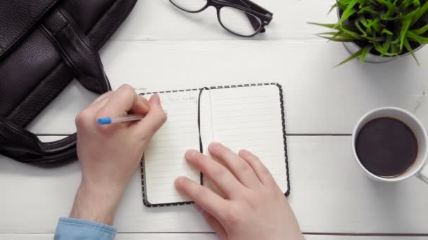 Top view male hands writing in notebook on white desk from above — Stock Video