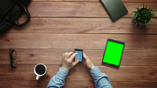 Üstten Görünüm erkek eller yeşil ekran yukarıdan beyaz masa üzerinde yalan ile smartphone ve dijital tablet üzerinde büyük veri grafikler ve çizelgeler ile çalışma — Stok video