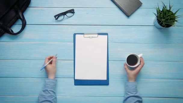 Bovenaanzicht mannelijke handen met pen op Bureau met Klembord met papier van boven — Stockvideo