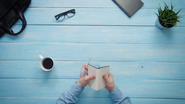 Mani maschili vista dall'alto scrittura in notebook su scrivania bianca dall'alto — Video Stock