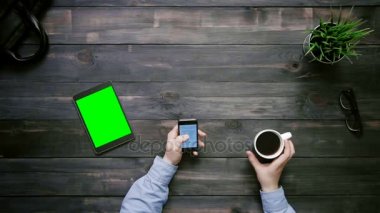 Üstten Görünüm erkek eller yeşil ekran yukarıdan beyaz masa üzerinde yalan ile smartphone ve dijital tablet üzerinde büyük veri grafikler ve çizelgeler ile çalışma