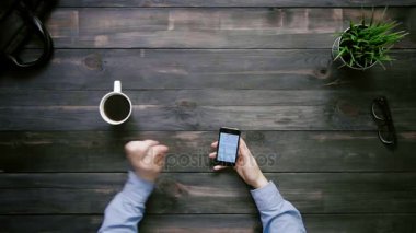 Üstten Görünüm erkek el smartphone cep telefonu ile yukarıdan beyaz masa üzerinde büyük veri grafikler ve çizelgeler ile çalışma