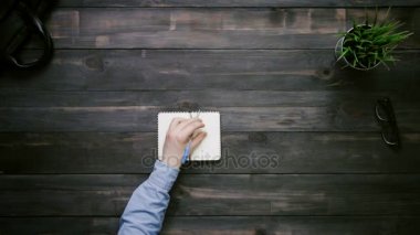 Üstten Görünüm erkek eller not defterinde yukarıdan beyaz masa üzerine yazma