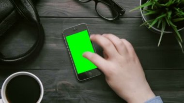 Üstten Görünüm erkek el ile yukarıdan beyaz masada Yeşil perde smartphone üzerinde birden çok hareketleri gösteren