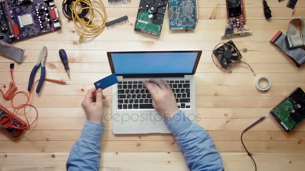 Top view computer technician at wooden desk with tools and electronic components buying computer components on line — Stock Video