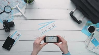 Üstten Görünüm yolcuları el Beyaz ahşap masa başında airplance bilet akıllı telefon ile fotoğraf çekimi