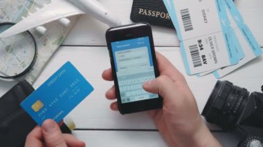 Üstten Görünüm yolcuları eller için uçak bileti Beyaz ahşap masa başında smartphone kullanarak satırındaki ödeme