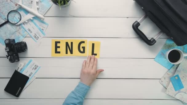 Top view time lapse hands laying on white desk word "ENGLAND" decorated with travel items — Stock Video