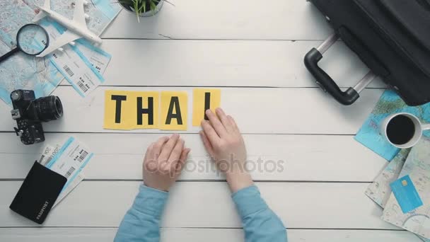 Top view time lapse hands laying on white desk word "THAILAND" decorated with travel items — Stock Video