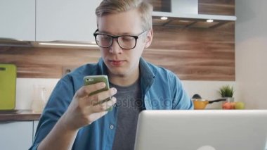 Genç adam, evde çalışma dizüstü bilgisayar ve smartphone kullanarak office