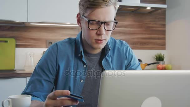 Junger Mann kauft online mit Kreditkarte und Laptop ein — Stockvideo