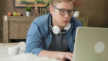 Genç adam evde dizüstü bilgisayar kullanıyor.