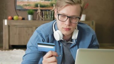 Genç adam alışveriş online kullanarak kredi kartı ve dizüstü bilgisayar