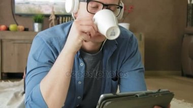 Dijital tablet kulaklıklar üzerinde akış film izlerken gülmekten genç adam