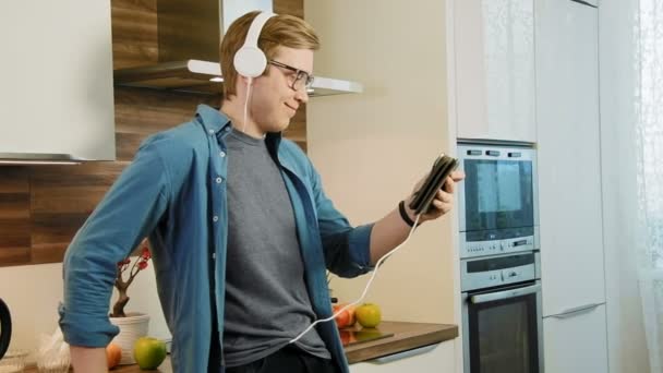 Młodzi, śmiejąc się człowiek oglądania odtwarzanego filmu na cyfrowej tablet jedzenie zbóż ze słuchawkami — Wideo stockowe